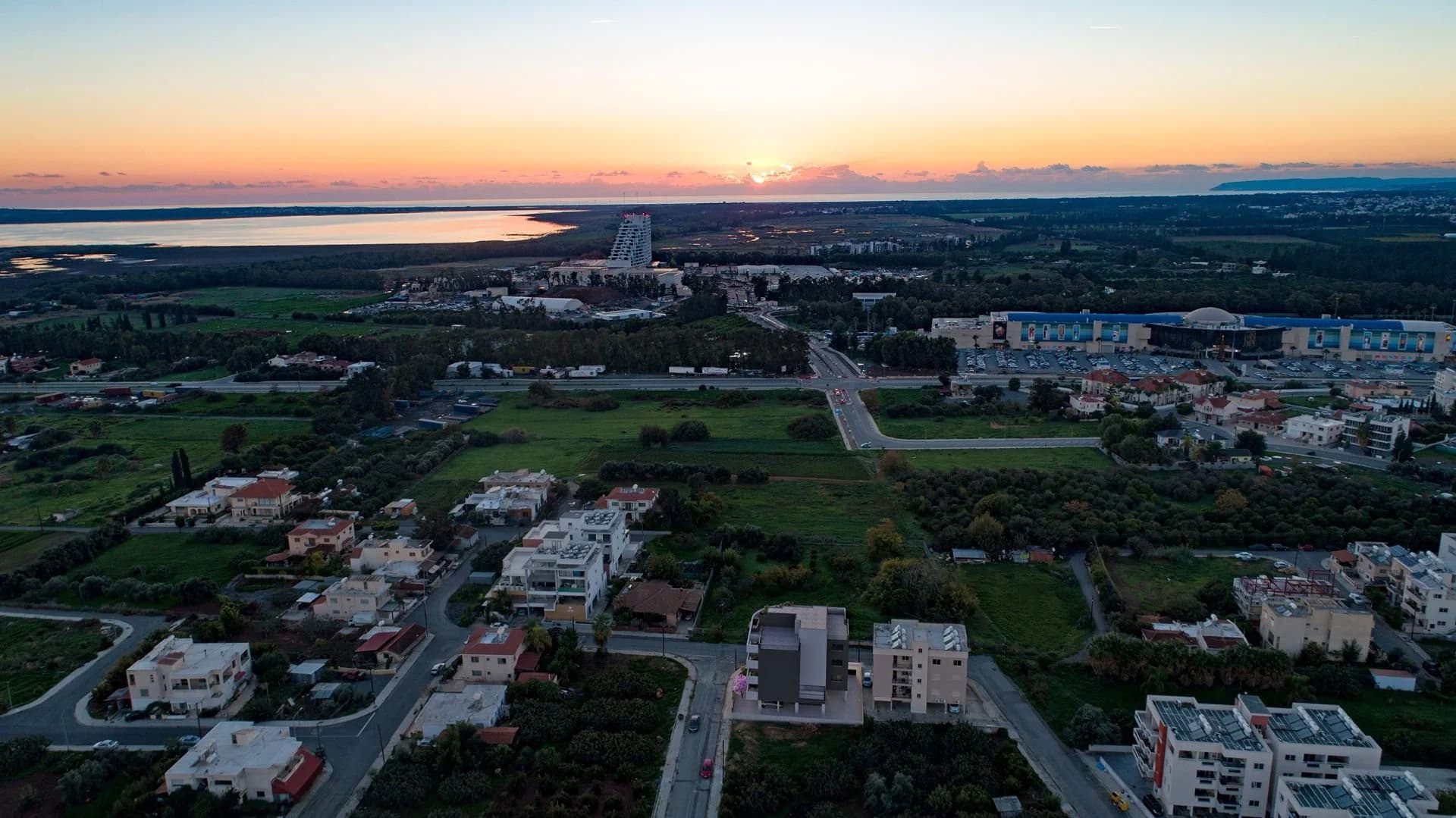 Aerial view of Zakaki around FLOW at sunset, with the salt lake and the sea beyond
