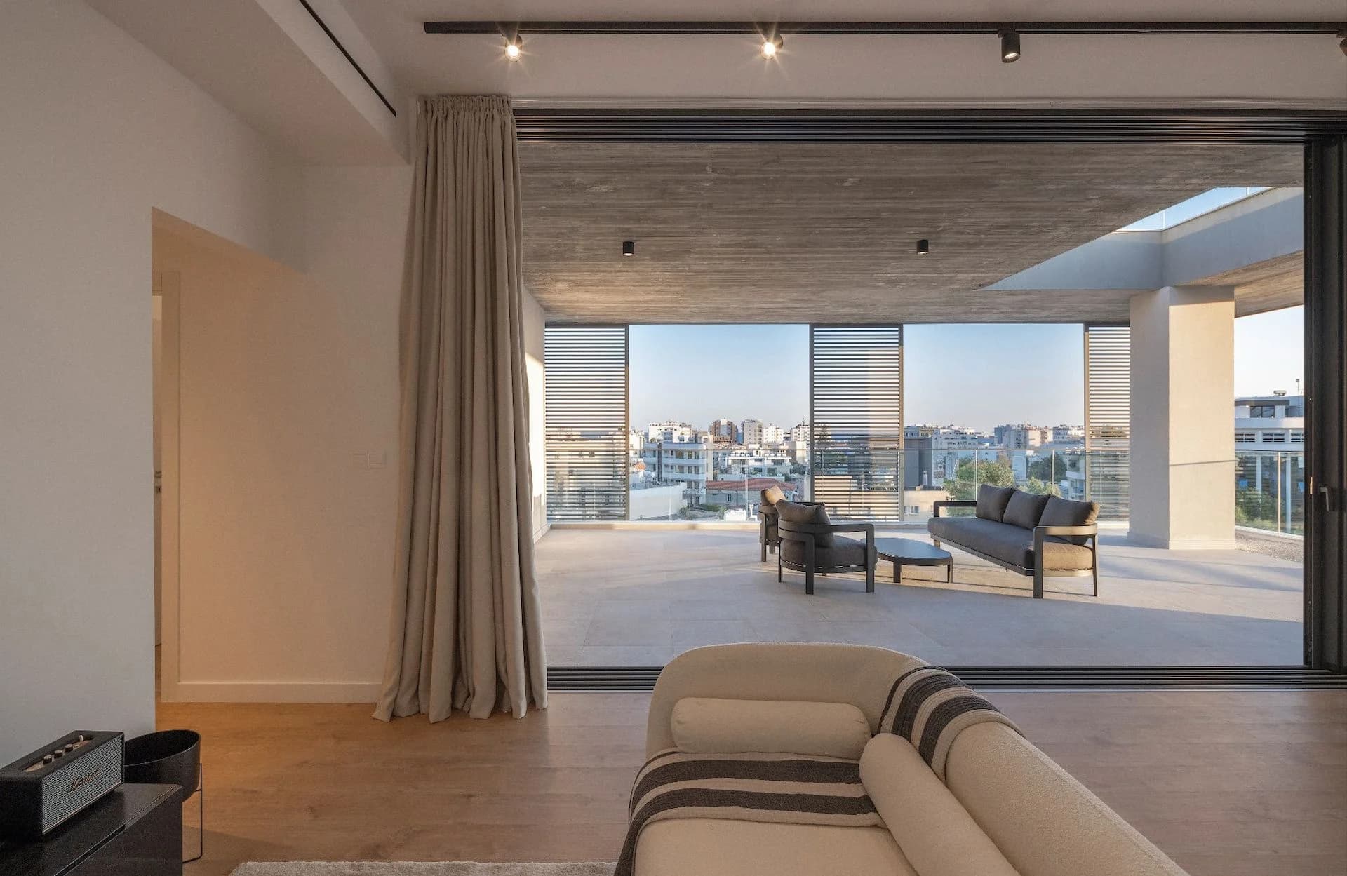 SEQUOIA terrace framed by sliding louvred screens, the city beyond