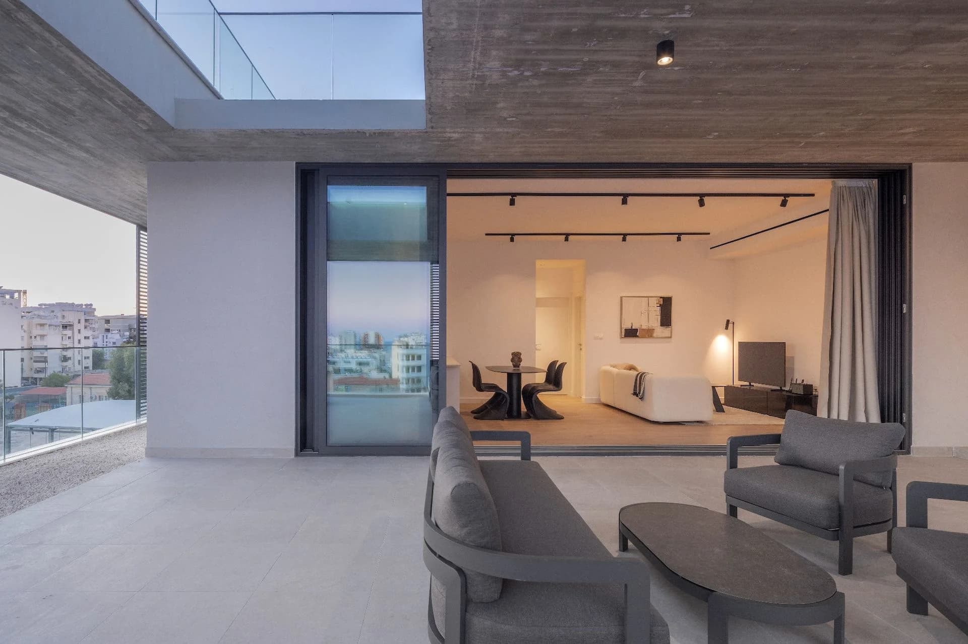 SEQUOIA terrace lounge at dusk, the lit apartment behind
