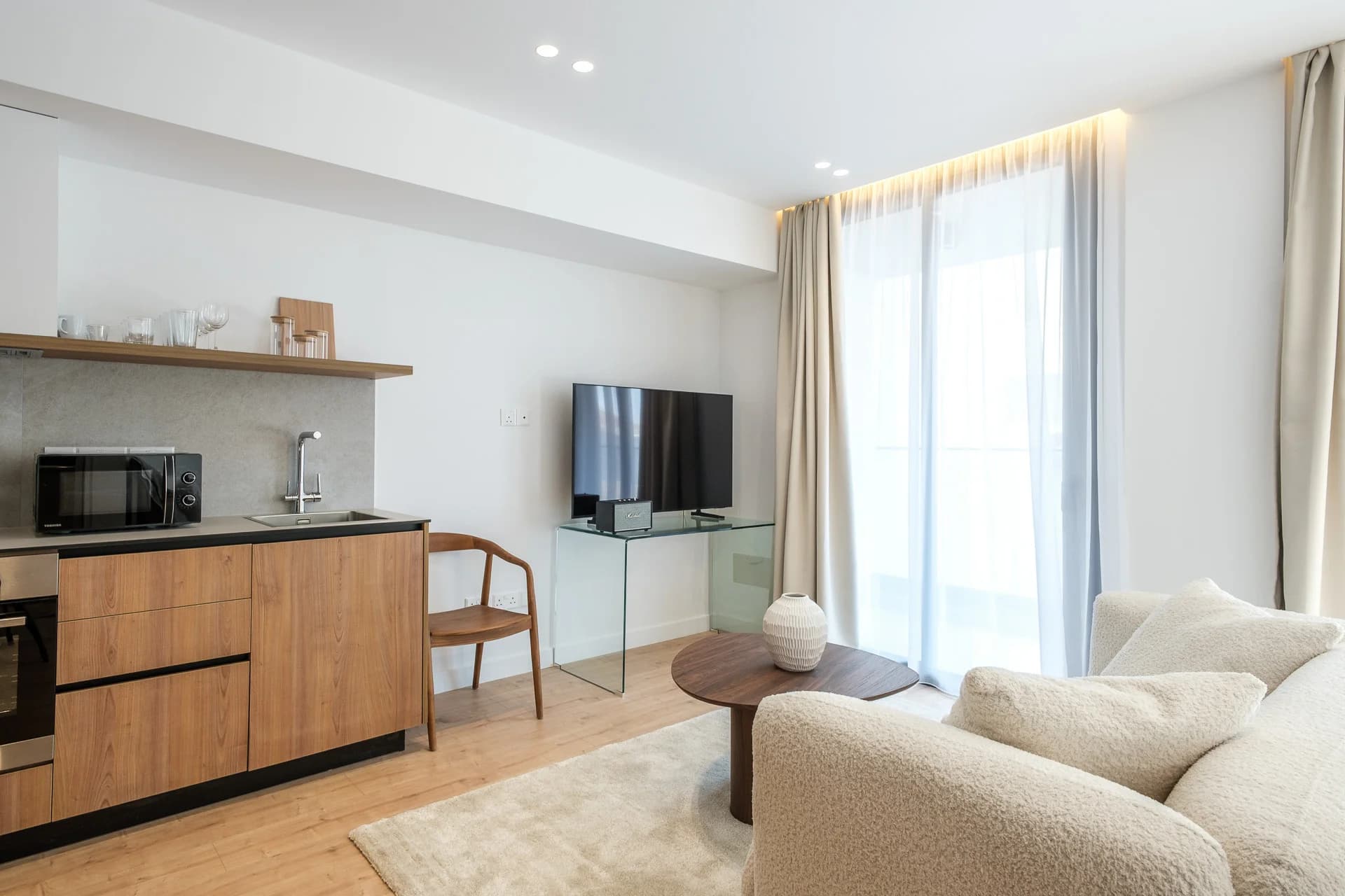 STAY 1 studio with a timber kitchen, sofa and full-height curtains