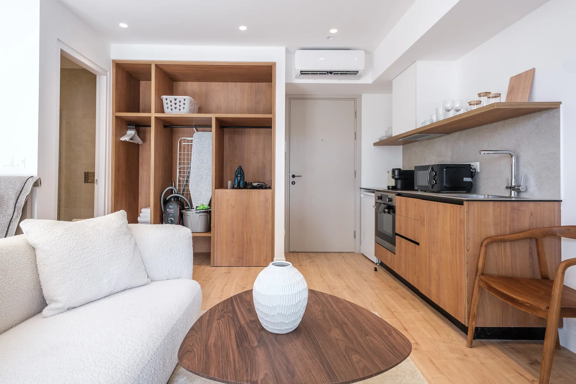 STAY 1 studio with a white sofa, oak shelving and a compact kitchen