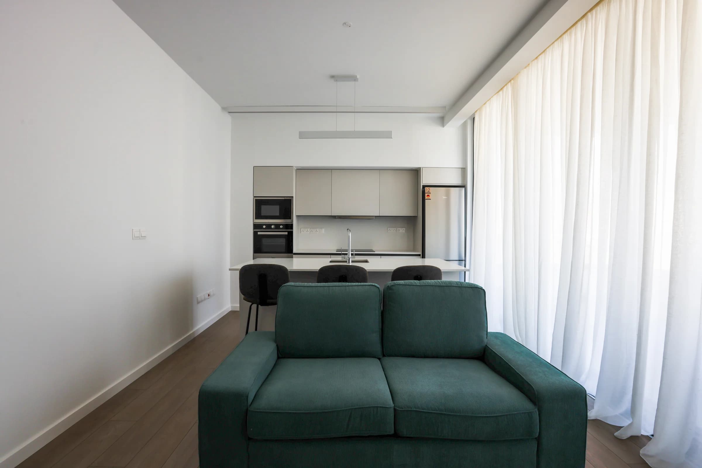 UKIYO living room with a green sofa and a white kitchen beyond