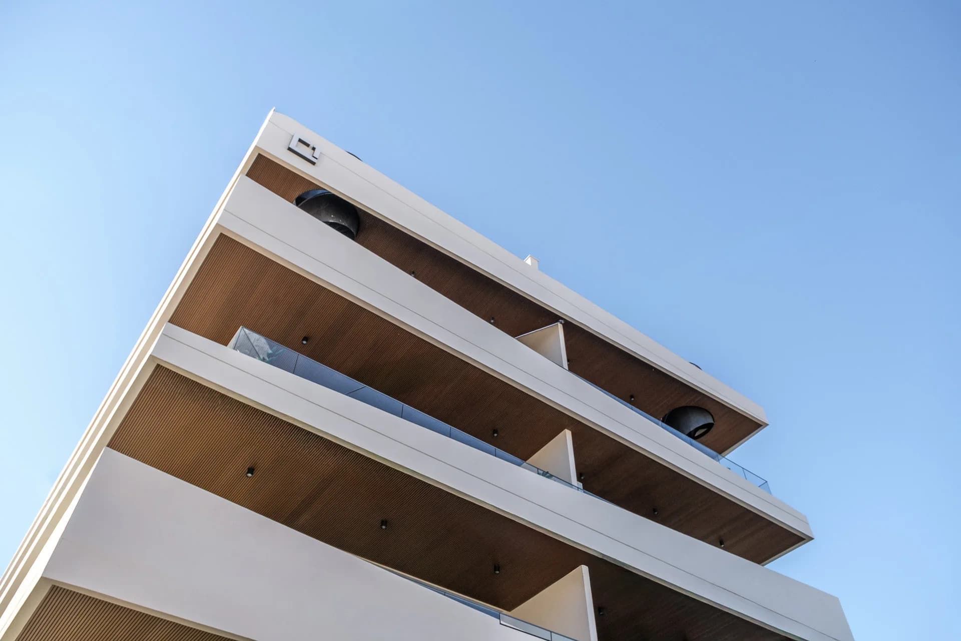 URBN's stacked balconies seen from below, timber soffits and glass railings
