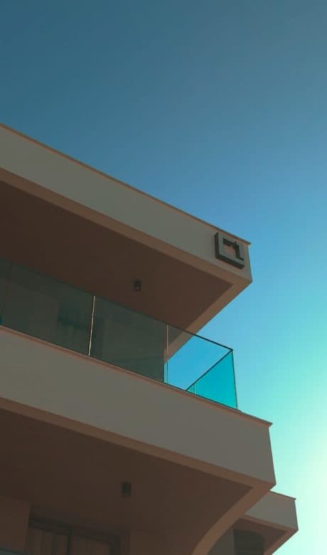 פינת מרפסת של SquareOne עם מעקה זכוכית על רקע שמיים בגוון טורקיז