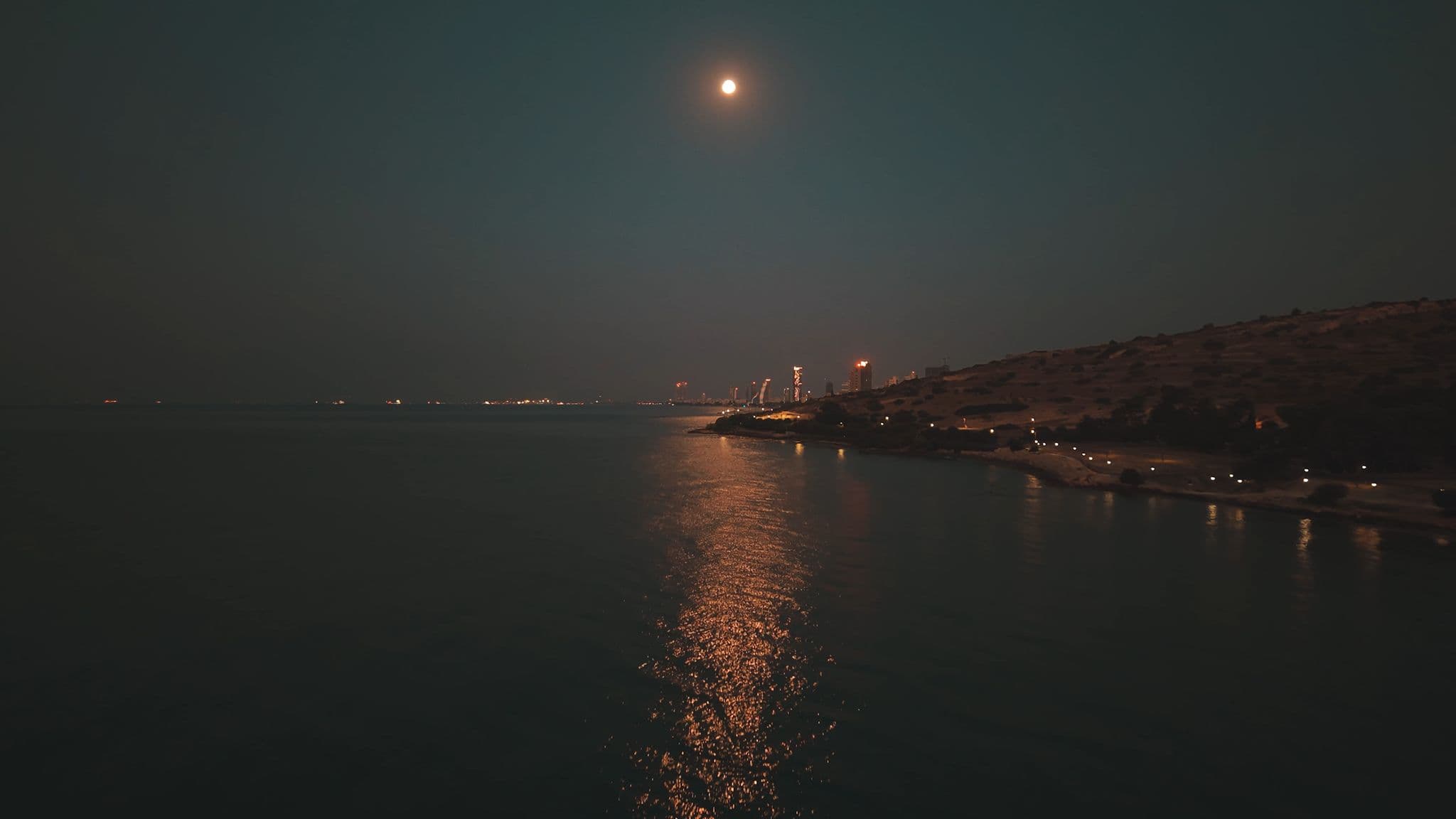 קו החוף של לימסול בלילה תחת ירח מלא